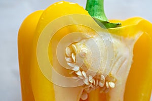 Close-up of yellow bell pepper cut. Matured shiny pulp with seeds
