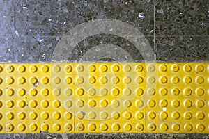 Close up yellow braille block on dark granite tile floor