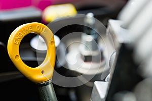 Close-up of a yellow engine oil dipstick.