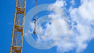 Close up of a yellow and green crane boom with main block and jib against a clear blue sky. Tower building cranes