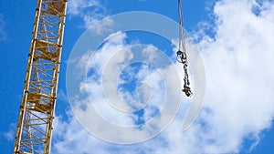 Close up of a yellow and green crane boom with main block and jib against a clear blue sky. Tower building cranes