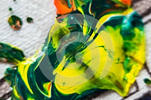 Close up of yellow, green and red paint on white canvas. Abstract background.