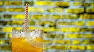 Close-up of yellow lemonade on a racy brick wall background. Summer drink with ice, orange juice
