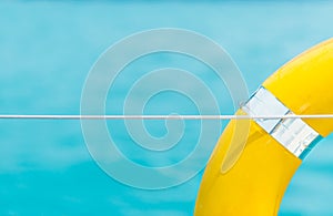 Close-up Yellow life ring hanging on boat with ocean background.