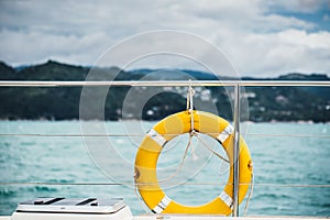 Close-up Yellow life ring hanging on boat with ocean background.