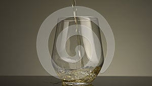 Close-up of yellow liquid being poured into transparent glass. Stock footage. Yellow drink is poured into transparent