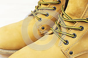 Close-up Yellow men`s work boots from natural nubuck leather on wooden white background. Trendy casual shoes, youth style. Concep