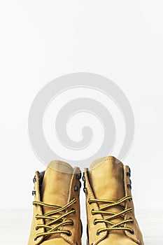 Close-up Yellow men`s work boots from natural nubuck leather on wooden white background. Trendy casual shoes, youth style. Concep