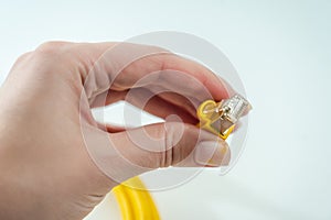 Close up of yellow RJ-45 cable on hand. 