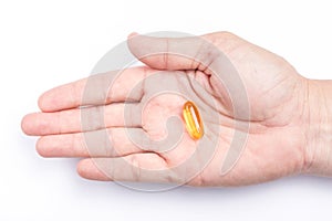 Close up yellow soft gel capsule in male hand with white background, concept of essential oil supplement intake.