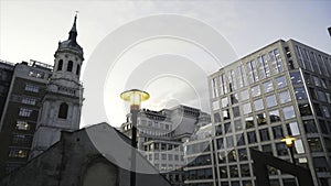 Close-up of yellow street lights in the center of London near the modern glass skyscrapers against the blue evening sky