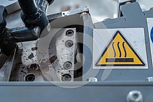 Warning hot surface symbol on industrial machine, close-up