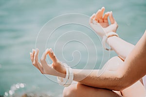 Close up Yoga Hand Gesture of Woman Doing an Outdoor meditation. Blurred sea background. Woman on yoga mat in beach