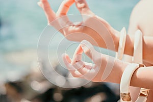 Close up Yoga Hand Gesture of Woman Doing an Outdoor meditation. Blurred sea background. Woman on yoga mat in beach