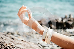 Close up Yoga Hand Gesture of Woman Doing an Outdoor meditation. Blurred sea background. Woman on yoga mat in beach