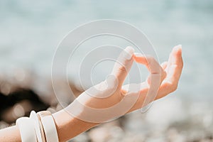 Close up Yoga Hand Gesture of Woman Doing an Outdoor meditation. Blurred sea background. Woman on yoga mat in beach