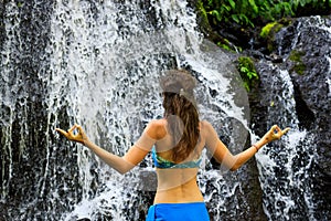 Close up of yoga woman in front of waterfall. Hands in gyan mudra. View from back. Pucak Manik waterfall Wanagiri, Bali, Indonesia