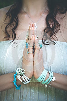 close up of yoga woman hands in namaste gesture with lot of boho style jewelry rings and bracelets outdoor