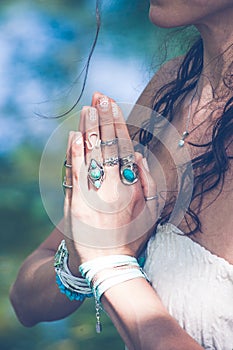 close up of yoga woman hands in namaste gesture with lot of boho style jewelry rings and bracelets outdoor