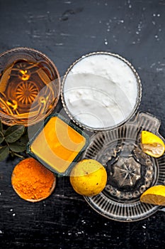 Close up of yogurt or curd face pack with honey,lemon juice,turmeric powder for acne skin on wooden surface in a glass container w