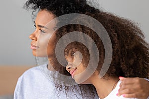 Close up young African American mother hugging teen daughter