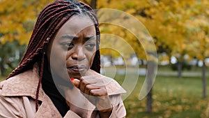 Close-up young african american woman standing outdoors coughing holding neck suffering from sore throat feeling