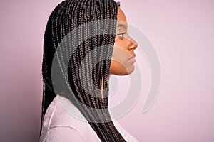 Close up of young african american woman wearing pink sweater over isolated background looking to side, relax profile pose with