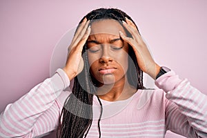 Close up of young african american woman wearing pink sweater over isolated background suffering from headache desperate and