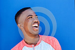 Close up young african man laughing against blue background