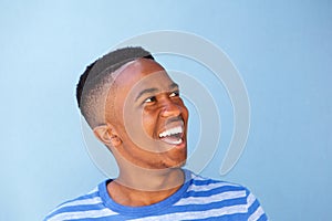 Close up young african man laughing against blue wall