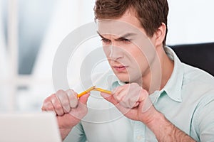 Close up of young angry businessman breaking