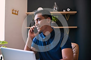 A close up of a young Asian businessman taking a call at his office desk