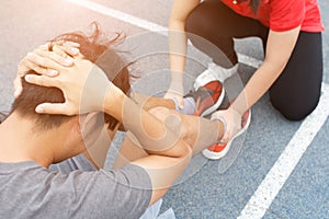 Close up of young asian couple doing sit-ups on the blue running track in stadium