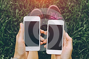 Close up of young asian healthy women`s hands holding two cell telephone with blank copy space.