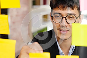 Close up of  young asian man writing on sticky note at office, business brainstorming creative ideas, office lifestyle, success in