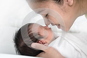 Close up young asian mother kissing her newborn baby. Mom`s love newborn.