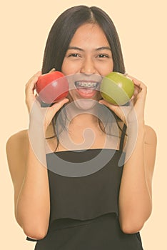 Close up of young Asian teenage girl putting green and red apple near the face