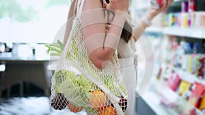 Close-up of young Asian woman buying fresh organic food with reusable tote bag in grocery market store- zero waste, eco