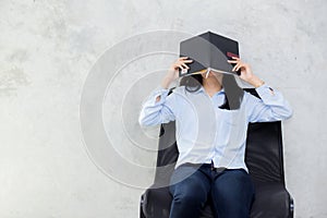 Close up of young asian woman reading book and hiding face on cement background