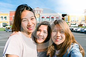 Close up of young Asian women group selfie themselves in the pastel buildings city in nice sky morning.