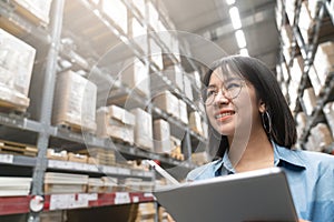 Close up of young attractive asian woman, auditor or trainee staff work stocktaking inventory in warehouse store by computer
