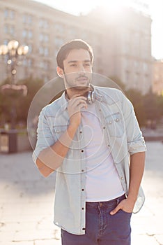 Close up of a young attractive brunete guy, walking in the spring city outdoors, in casual comfortable outfit and with big