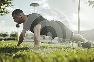 Close up of young attractive man exercising plank outdoors. Side view.