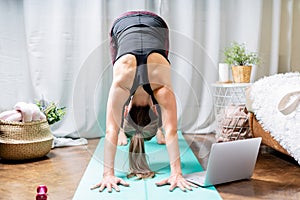 Close up Young attractive sporty woman practicing yoga, standing Downward Facing Dog pose, working out at home in living room.