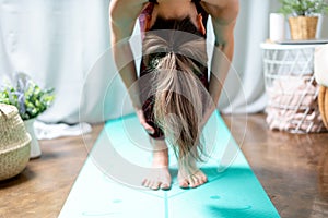 Close up Young attractive sporty woman practicing yoga, standing forward bend exercise, head to knees, uttanasana pose