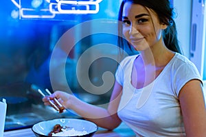 Close up of young attractive woman eating asian food with chopsticks at cafe.