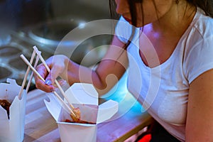 Close up of young attractive woman eating asian food with chopsticks at cafe.