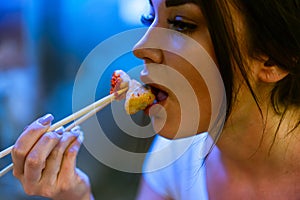 Close up of young attractive woman eating asian food with chopsticks at cafe.