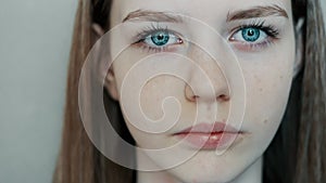 Close-up of young beautiful blue eyes, young teenager girl looks at the camera