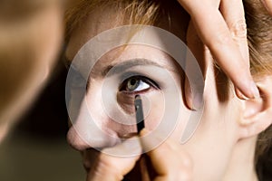 Close up of Young beautiful bride applying make-up by make-up artist